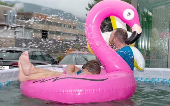 Pool vor dem Geschäftsgebäude mit pinken Flamingo zum aufblasen in dem ein Mann sitzt